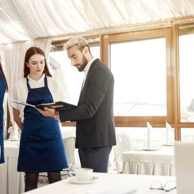Handsome young director of a restaurant is giving work instructions to waitresses